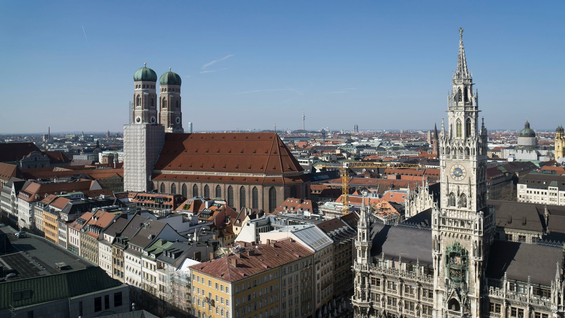 Blick über die Münchner Altstadt mit den Türmen der Frauenkirche und dem Neuen Rathaus am Marienplatz bei klarem Himmel